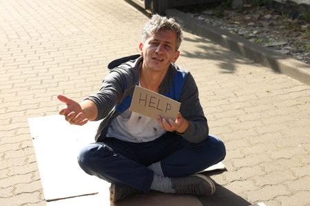 Homeless man with sign Help begging for money on carton outdoors