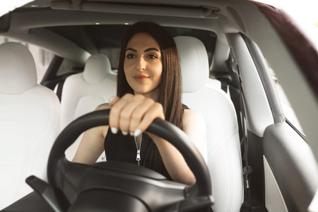 Woman behind steering wheel of modern car, view through windshield