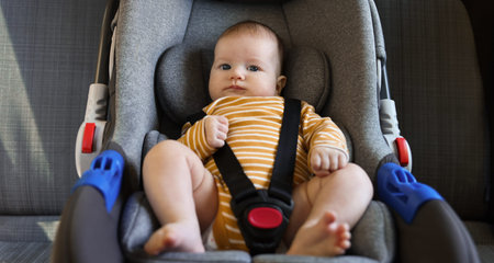 Cute little baby fastened in car seatの写真素材