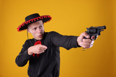 Man in black Flamenco hat with gun on yellow background
