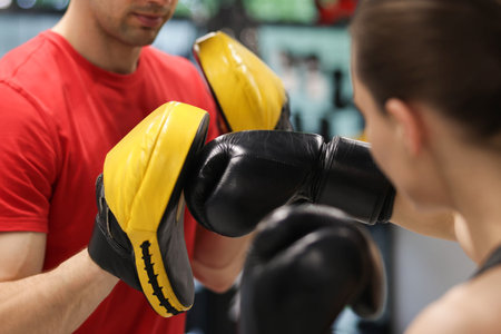 Young woman exercising with professional personal trainer in gym, closeup