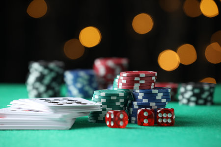 Casino chips, dice and playing cards on green table against blurred lights, closeupの写真素材