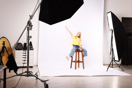 Little girl on white background in photo studio with professional equipment