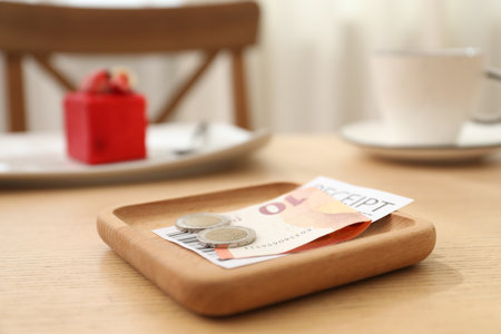 Tips and receipt on wooden table in restaurant, closeup. Gratuity for workの写真素材