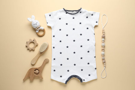 Baby romper and accessories on beige background, flat lay