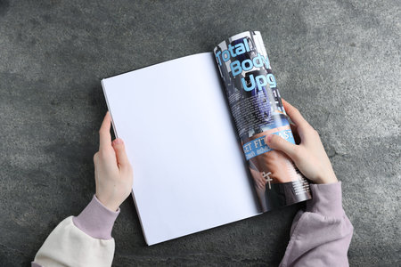 Woman reading magazine at gray table, top view. Mockup for design