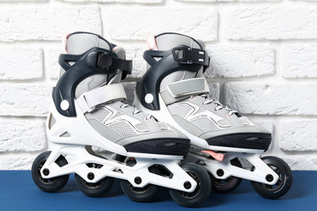 Pair of roller skates on blue table near white brick wall