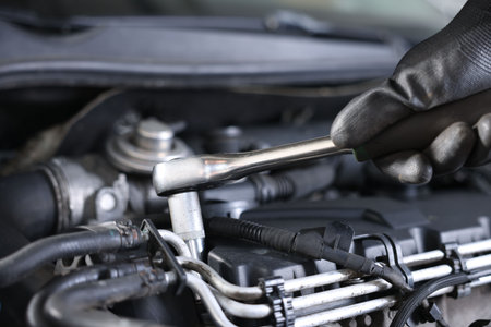 Auto parts. Professional mechanic with torque wrench fixing car indoors, closeup