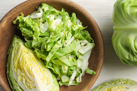 Fresh green cabbages on light wooden table, flat lay