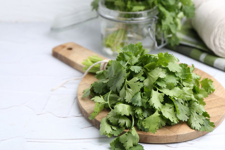 Fresh aromatic cilantro on white table, closeup. Space for text
