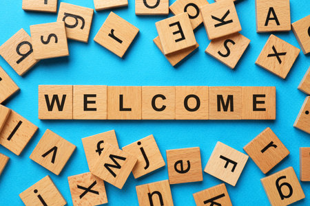 Word Welcome made of wooden cubes on light blue background, flat layの写真素材
