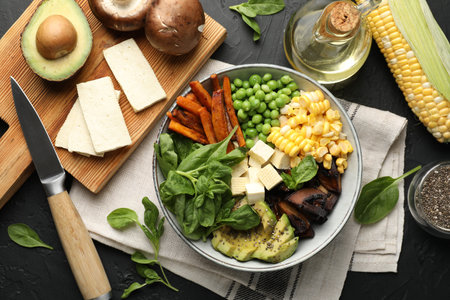 Healthy vegetarian food. Delicious Buddha bowl and ingredients on black table, flat lay