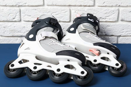 Pair of roller skates on blue table near white brick wall, closeup