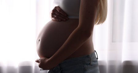 Beautiful pregnant woman near window at home, closeup
