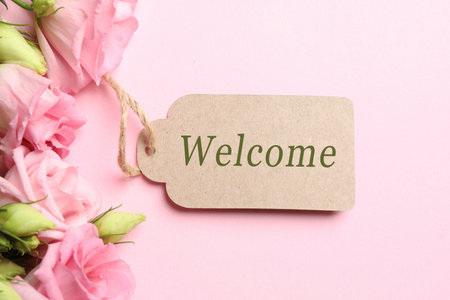 Welcome card and bouquet of eustoma flowers on pink background, top viewの写真素材