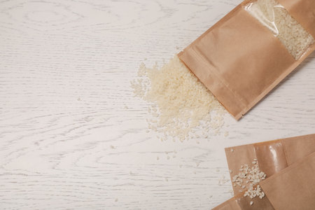 Zipper stand-up pouches with rice on white wooden table, flat lay. Mockup for designの写真素材