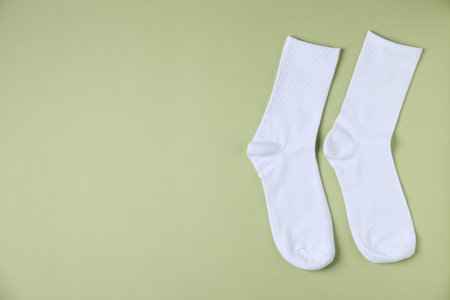 Pair of comfortable white socks on light green background, top view. Space for textの写真素材