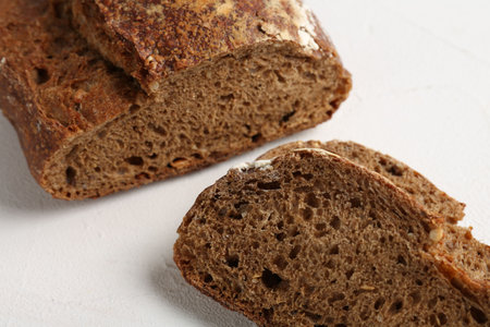 Pieces of fresh rye bread on white textured table, closeup