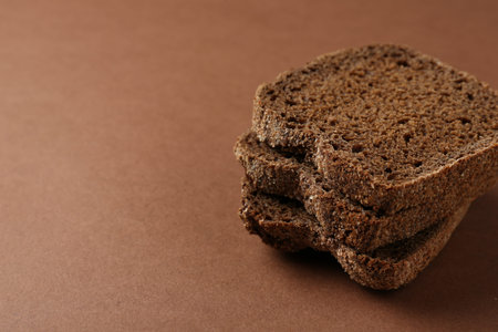 Pieces of fresh rye bread on brown background, closeup. Space for text