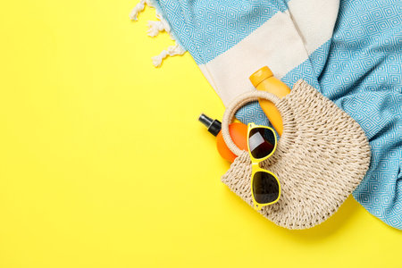 Flat lay composition with beach towel and other summer accessories on yellow background. Space for...