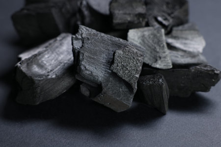 Pieces of black coals on grey table, closeup