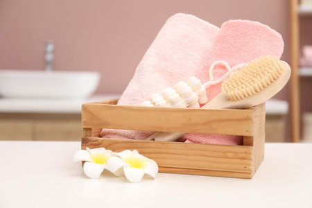 Colorful towels, brush, massage soap and plumeria flowers on white table indoorsの写真素材