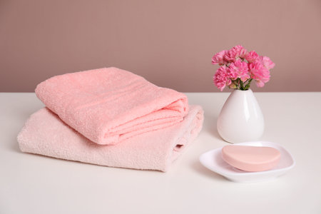 Stack of soft towels, flowers and soap on white tableの写真素材