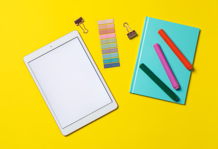 Tablet and different stationery on yellow background, flat layの写真素材