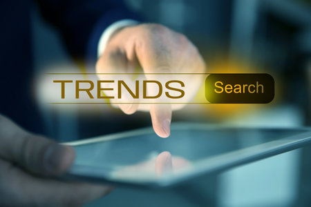 Businessman using tablet computer to find hot tendencies, new ideas, popular directions, closeup. Search bar with word Trendsの写真素材