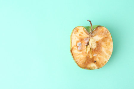 Half of spoiled apple on turquoise background, top view. Space for textの写真素材