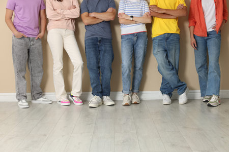 Group of teenagers near beige wall indoors, closeup