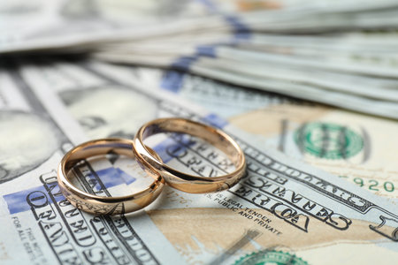 Two gold wedding rings on dollar banknotes, closeupの写真素材