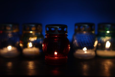 Many grave candles on black table against blue background, closeup