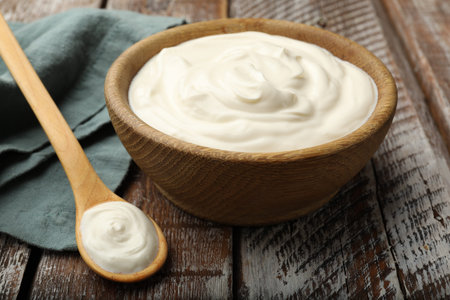 Tasty sour cream on wooden table, closeup