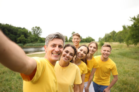 Team building. Group of happy people taking selfie outdoors