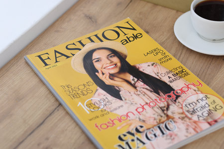 Fashion magazine and cup of coffee on wooden table indoors, closeupの写真素材