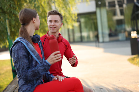Happy couple resting on bench after morning exercises outdoors. Space for textの写真素材