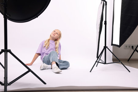 Little girl on white background in photo studio with professional equipmentの写真素材