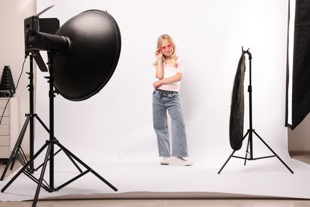 Little girl on white background in photo studio with professional equipmentの写真素材