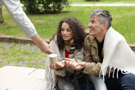 Man giving money to homeless people in park, closeup