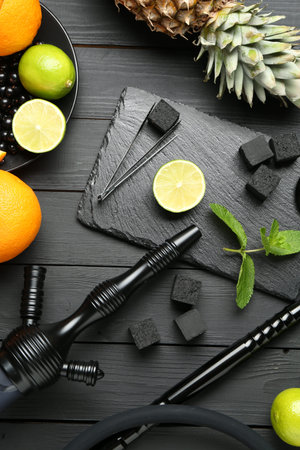 Hookah, coal and fresh fruits on black wooden table, flat lay