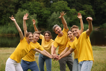 Team building. Group of happy people joining hands outdoors