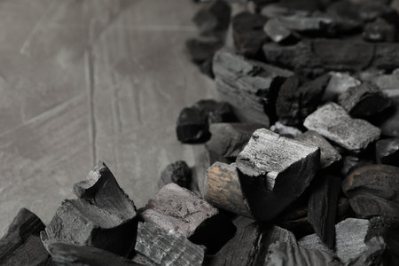 Pieces of black coals on grey table, closeup. Space for text