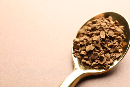 Spoon with granulated instant coffee on beige background, closeup. Space for textの写真素材