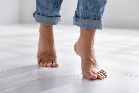 Woman walking on warm floor indoors, closeup. Heating system
