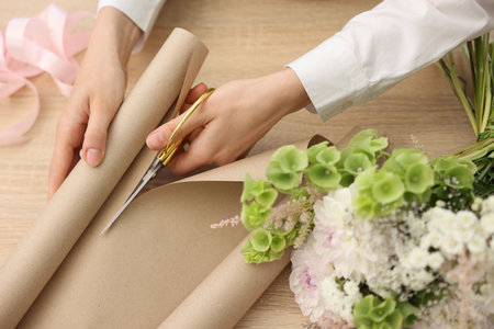 Florist making bouquet of flowers at wooden table, above viewの写真素材