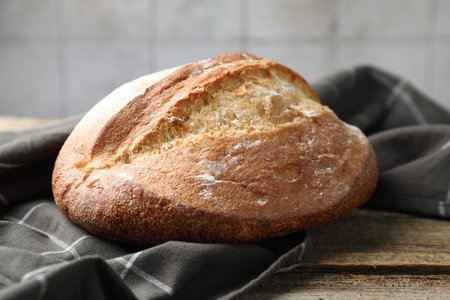 Loaf of fresh bread on wooden table, closeup