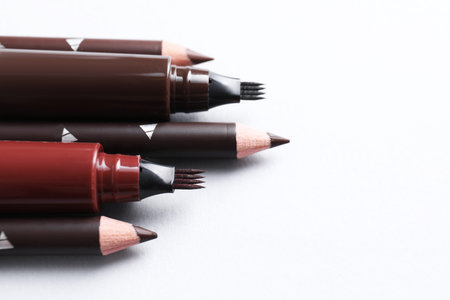 Different eyebrow pencils on white background, closeup. Space for text
