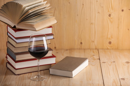 Glass of red wine and stacked books on wooden table. Space for textの写真素材