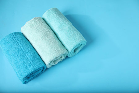 Different soft towels on light blue background, above view. Space for text